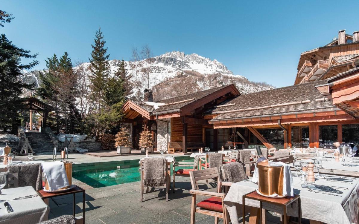 un restaurant avec des tables et des chaises à côté d'une piscine dans l'établissement Hôtel LE BLIZZARD, à Val dʼIsère