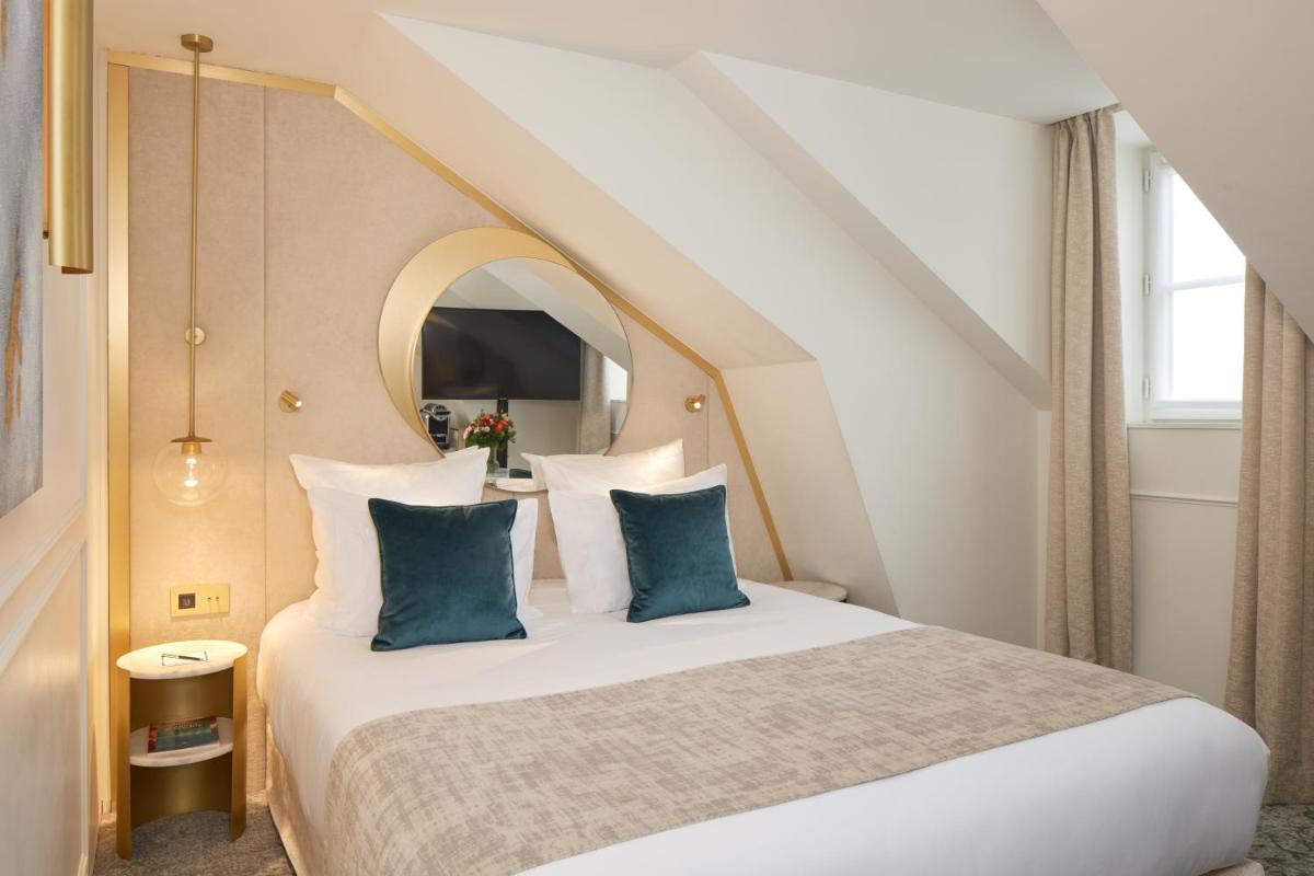 une chambre avec un grand lit aux oreillers bleus dans l'établissement Maison Albar - Le Vendome, à Paris