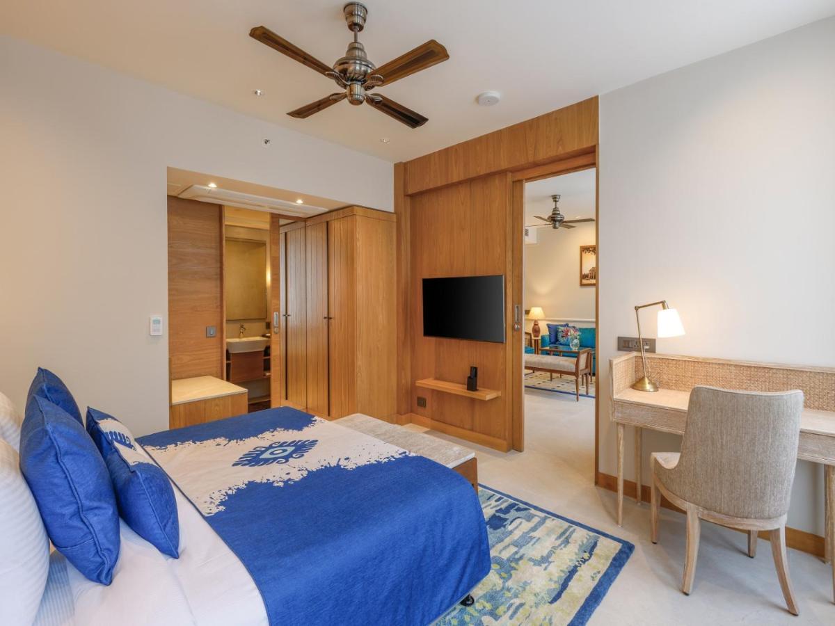 a bedroom with a bed and a television and a desk at The Astor - All Suites Hotel Candolim Goa in Candolim a bedroom with a bed and a television and a desk at The Astor - All Suites Hotel Candolim Goa in Candolim