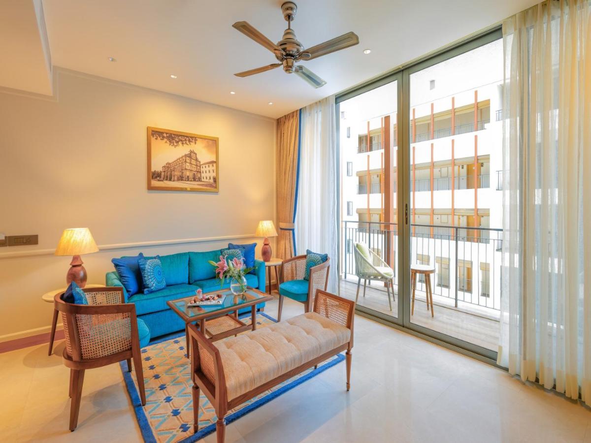 a living room with a blue couch and a large window at The Astor - All Suites Hotel Candolim Goa in Candolim a living room with a blue couch and a large window at The Astor - All Suites Hotel Candolim Goa in Candolim