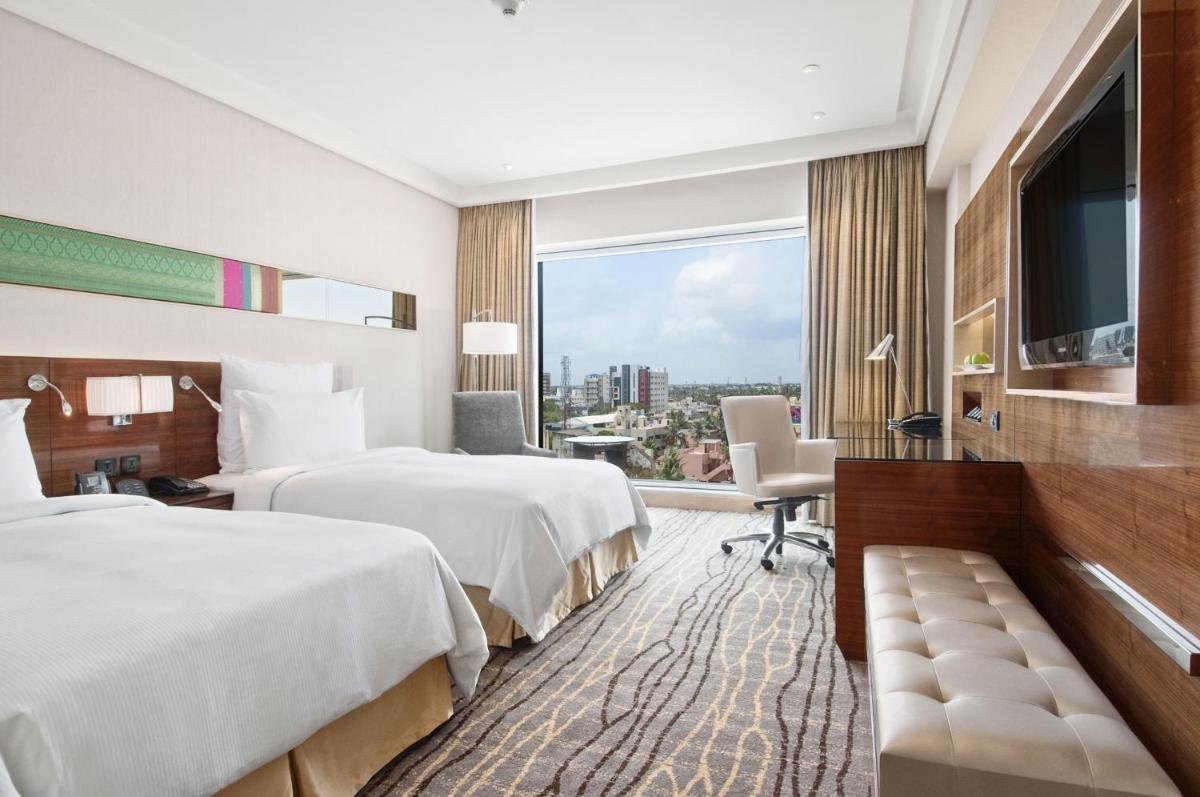 a hotel room with two beds and a large window at Hilton Chennai in Chennai