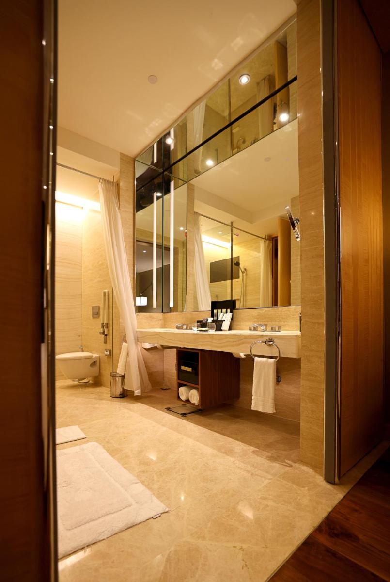 a bathroom with a sink and a large mirror at Conrad Pune in Pune
