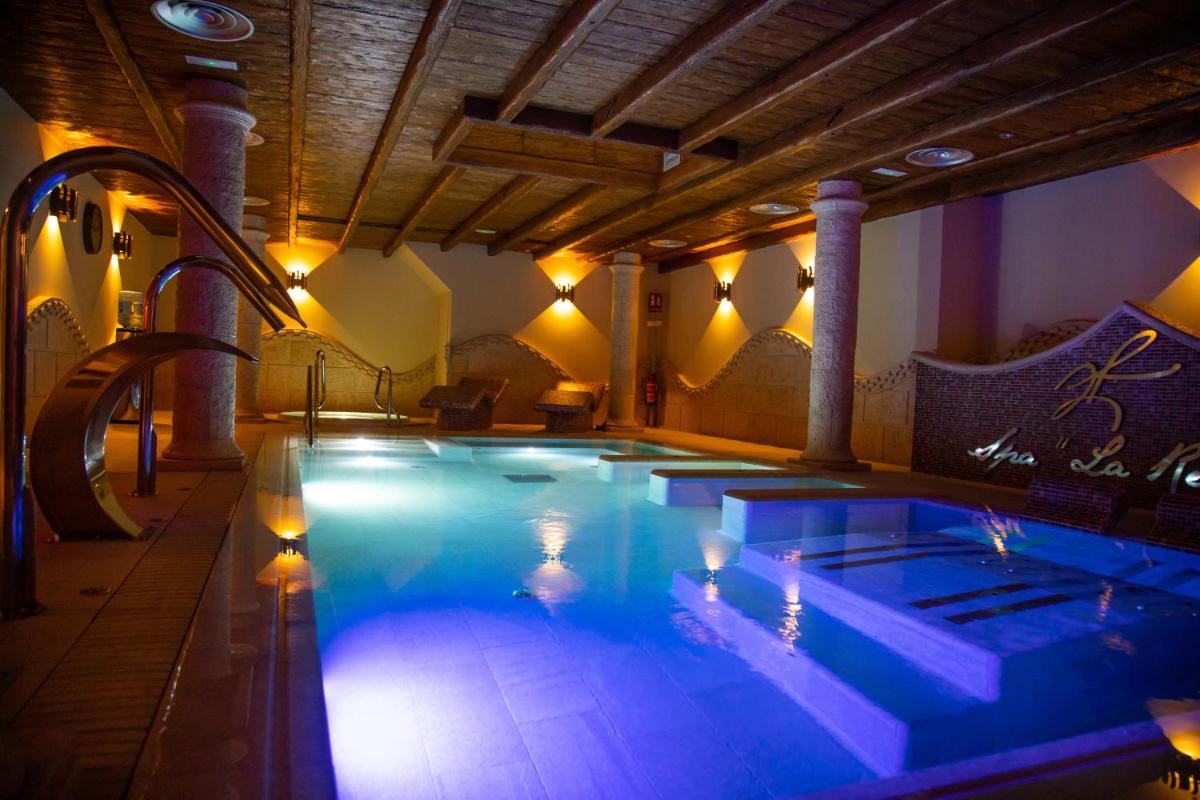 Una gran piscina con iluminación azul en un edificio. en Hotel Spa Viña Real, en Arévalo