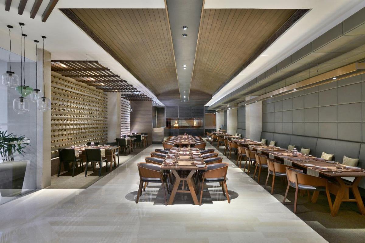 a restaurant with wooden ceilings and tables and chairs at The Westin Hyderabad Mindspace in Hyderabad