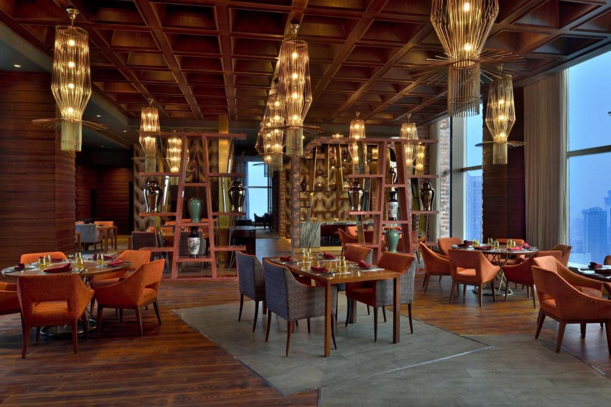a dining room with tables and chairs and chandeliers at The St. Regis Mumbai in Mumbai