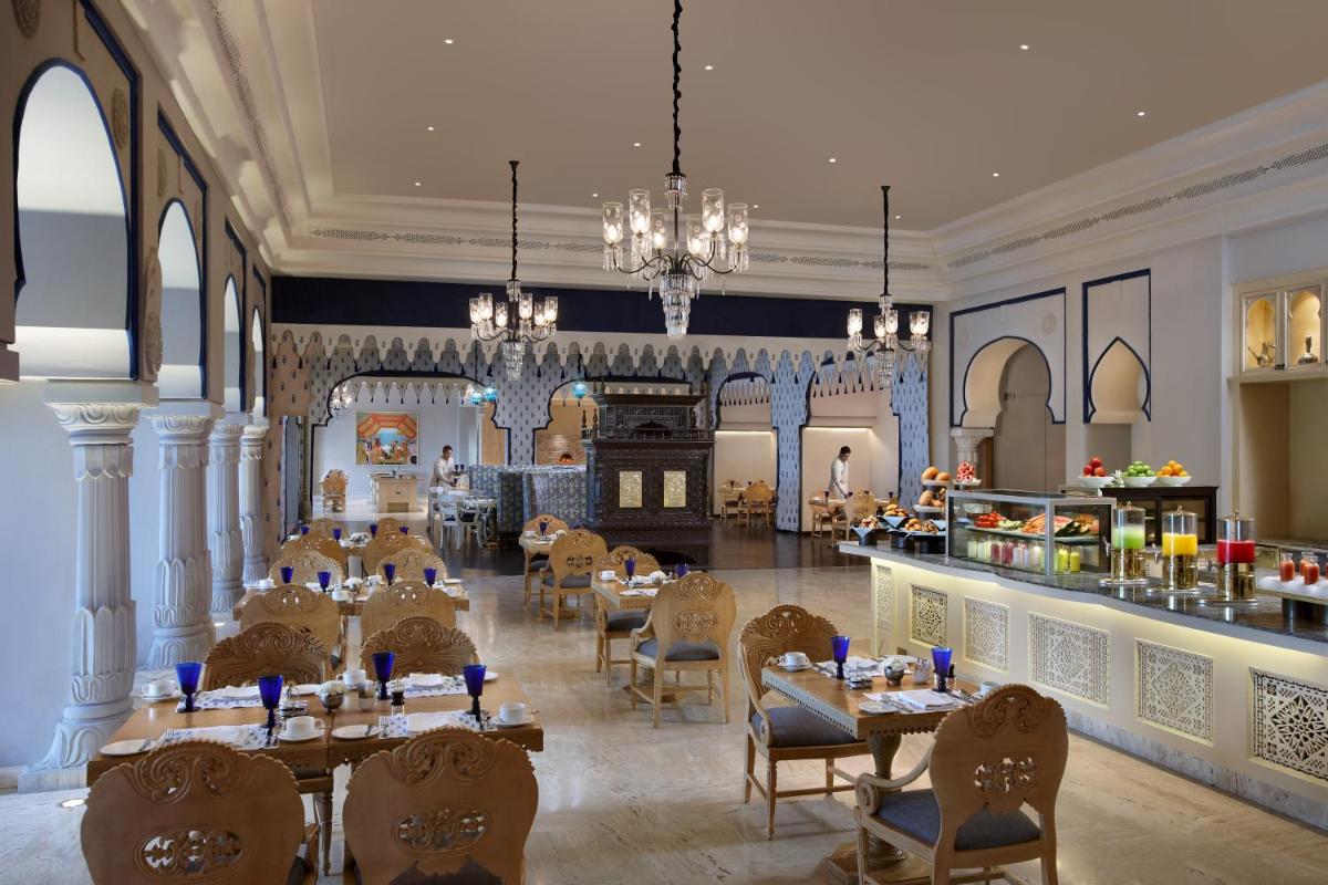 a restaurant with tables and chairs and a bar at Fairmont Jaipur in Jaipur