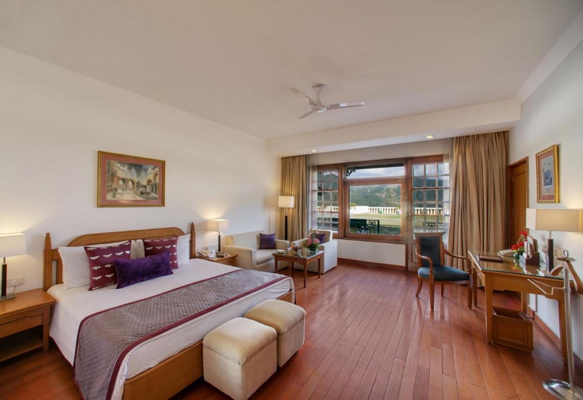 a hotel room with a large bed and a desk at Jaypee Residency Manor in Mussoorie a hotel room with a large bed and a desk at Jaypee Residency Manor in Mussoorie