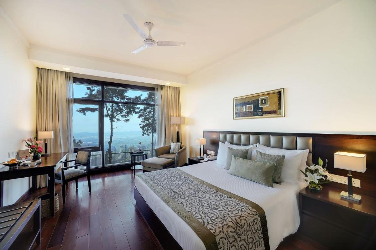 a bedroom with a bed and a desk and a window at Jaypee Residency Manor in Mussoorie