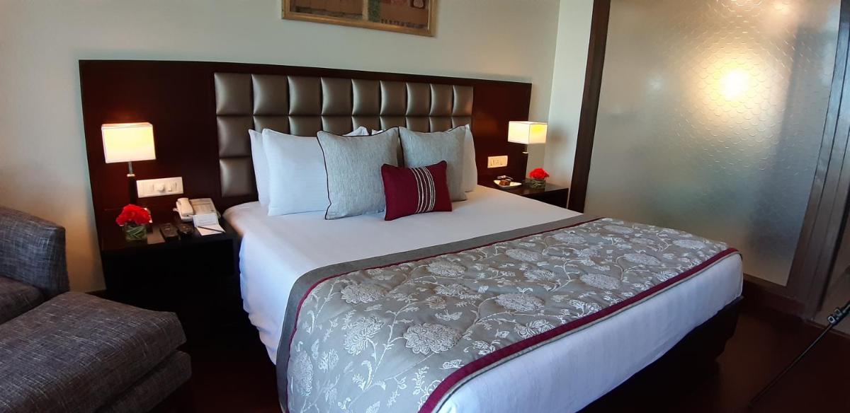 a large bed in a hotel room with two lamps at Jaypee Residency Manor in Mussoorie