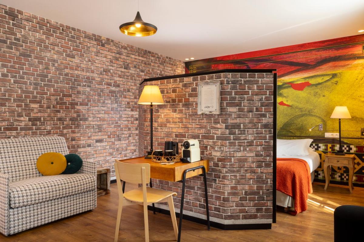 Cette chambre dispose d'un mur en briques, d'une table et d'une chaise. dans l'établissement Hotel L’Antoine, à Paris