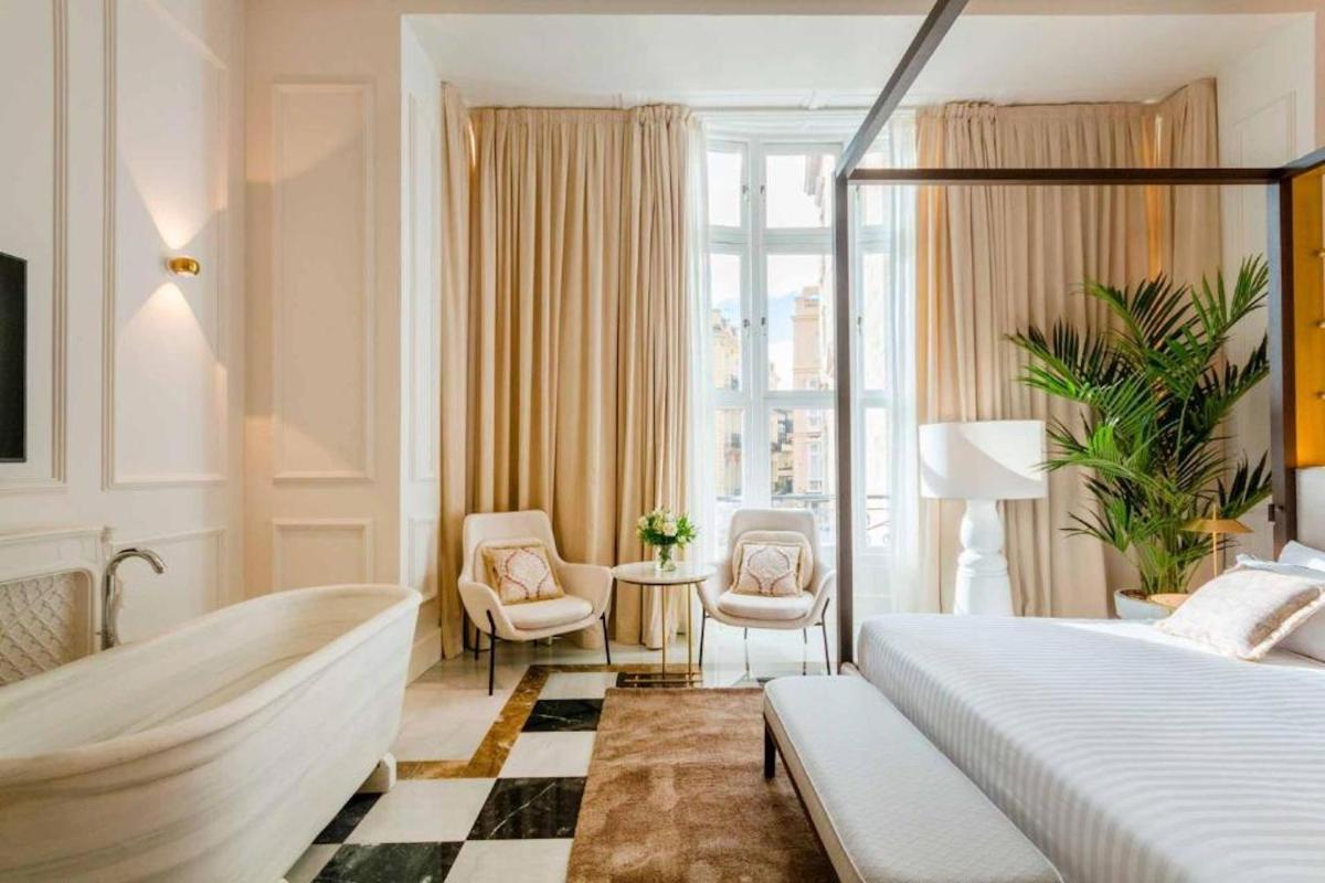 Un dormitorio con una cama y dos sillas y una ventana. en MYR Palacio Vallier, en Valencia