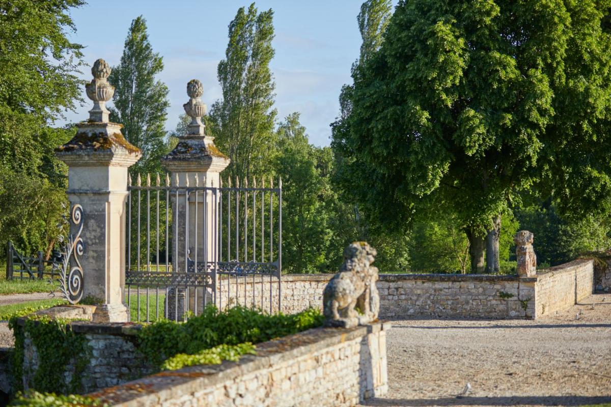un chien assis sur une clôture devant une porte dans l'établissement Chateau d'Audrieu, à Audrieu