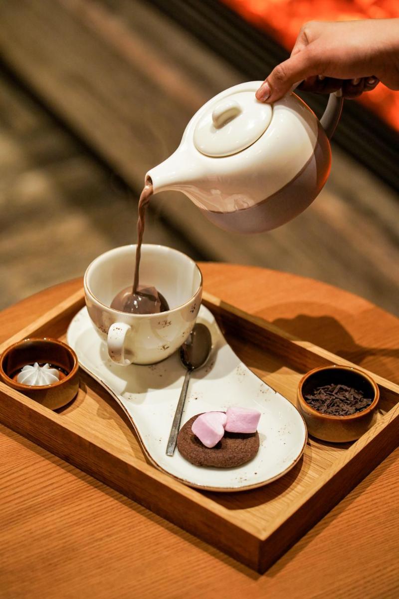 a person is pouring coffee into a cup on a tray at The Westin Resort & Spa Himalayas in Rishīkesh