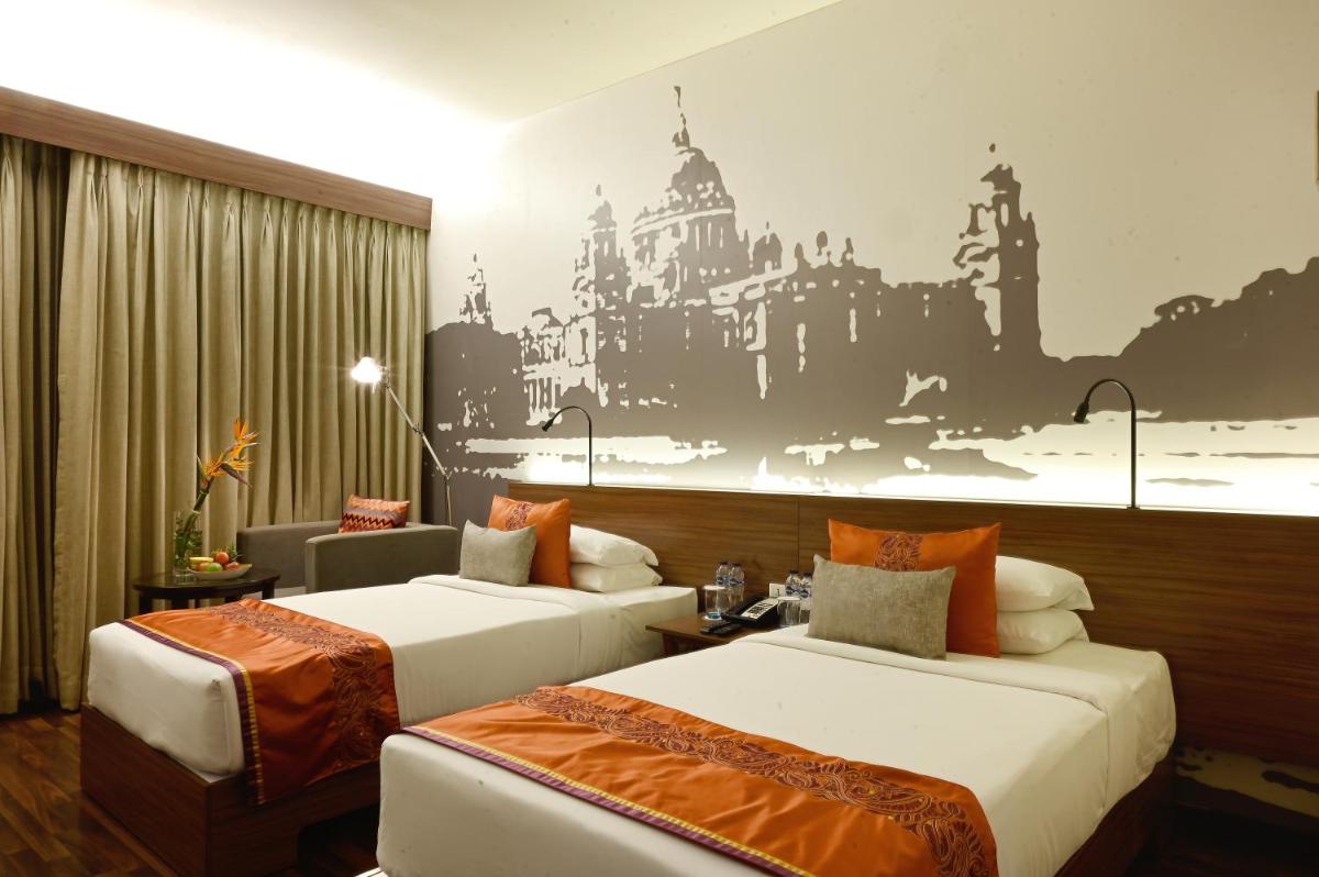 a hotel room with two beds and a painting on the wall at Vivanta Kolkata EM Bypass in Kolkata