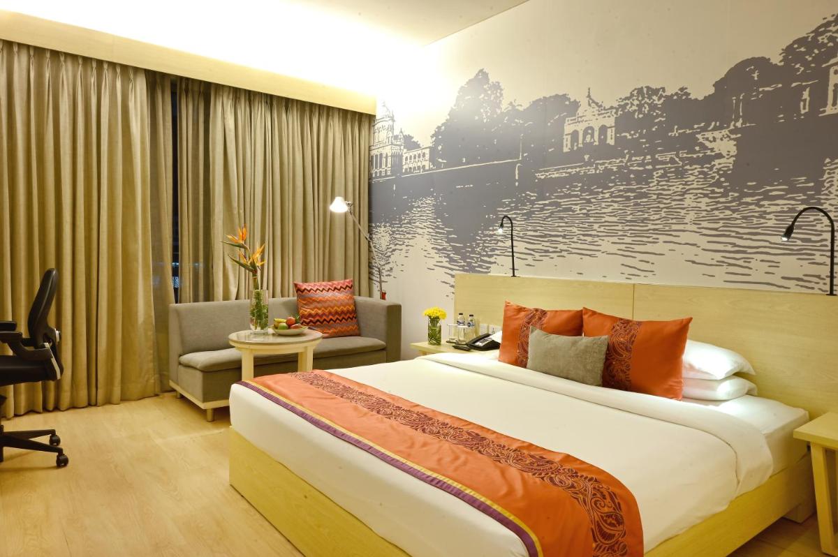 a hotel room with a bed and a chair at Vivanta Kolkata EM Bypass in Kolkata