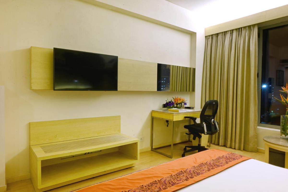 a bedroom with a bed and a desk and a television at Vivanta Kolkata EM Bypass in Kolkata