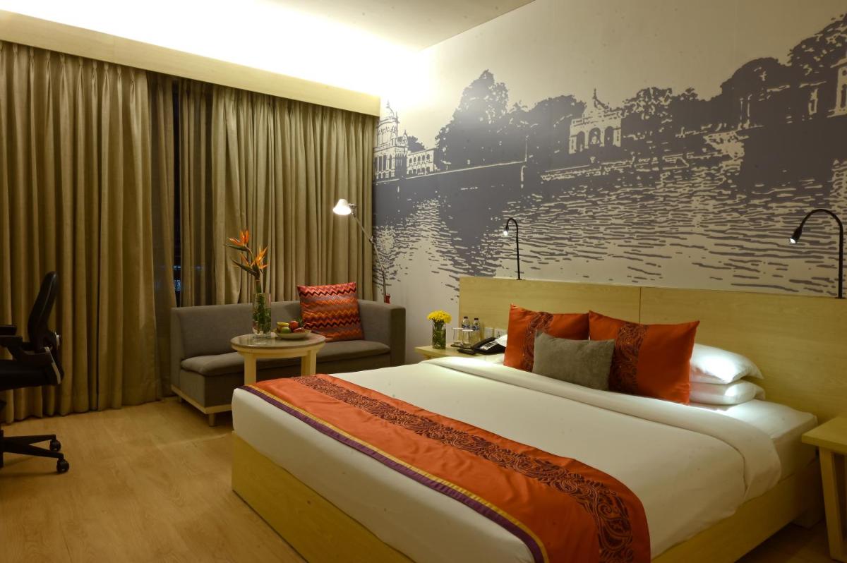 a hotel room with a large bed and a couch at Vivanta Kolkata EM Bypass in Kolkata
