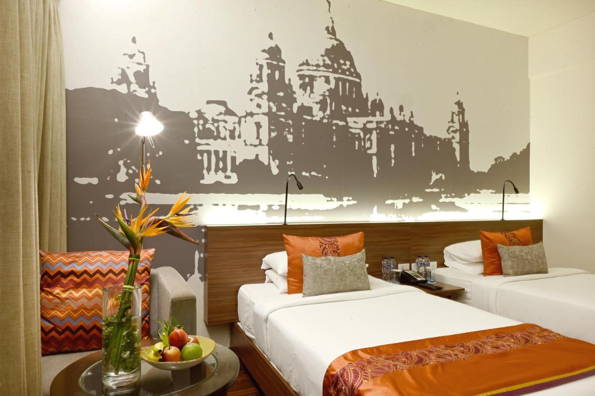 a hotel room with two beds and a table at Vivanta Kolkata EM Bypass in Kolkata