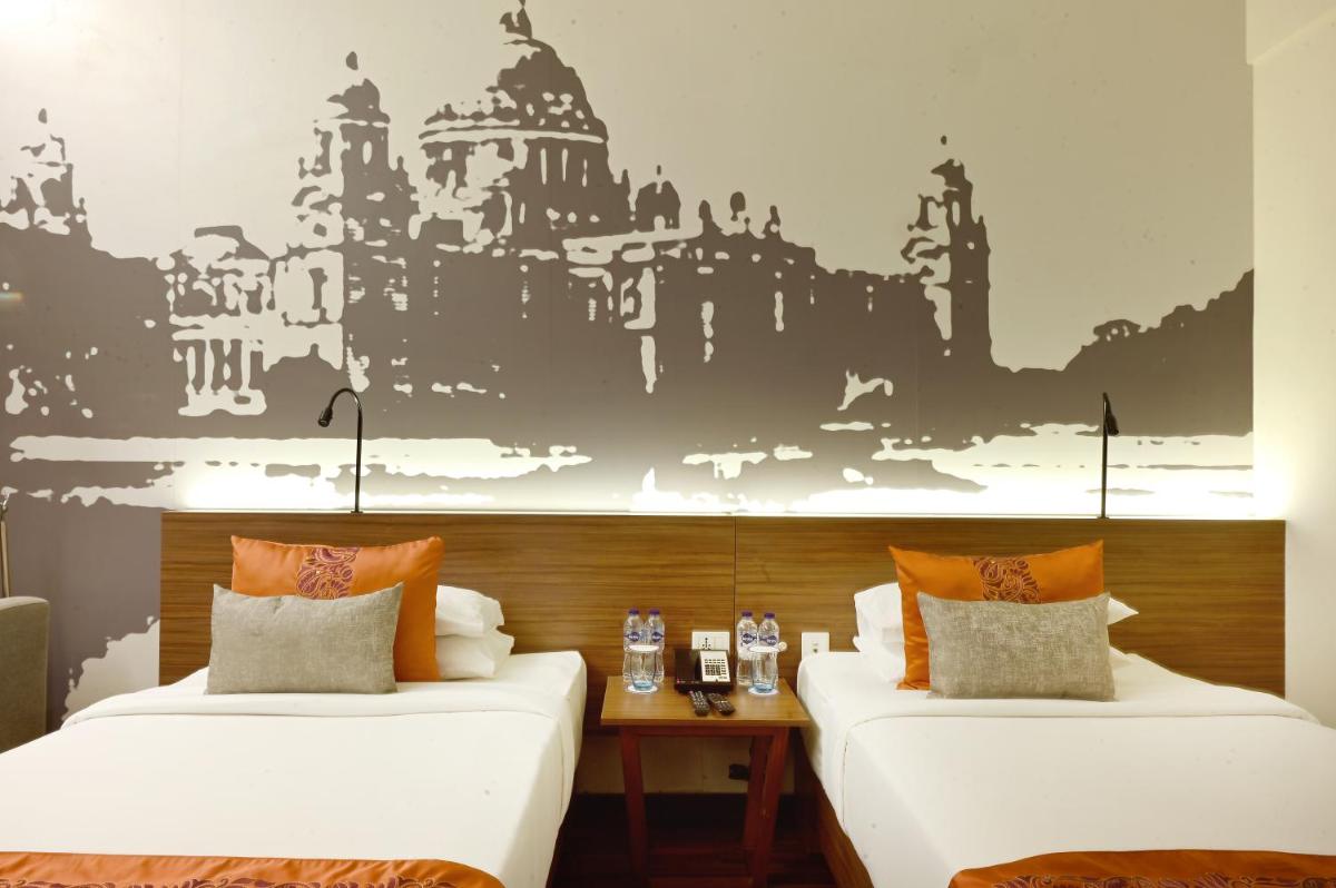 two beds in a room with a wall mural at Vivanta Kolkata EM Bypass in Kolkata