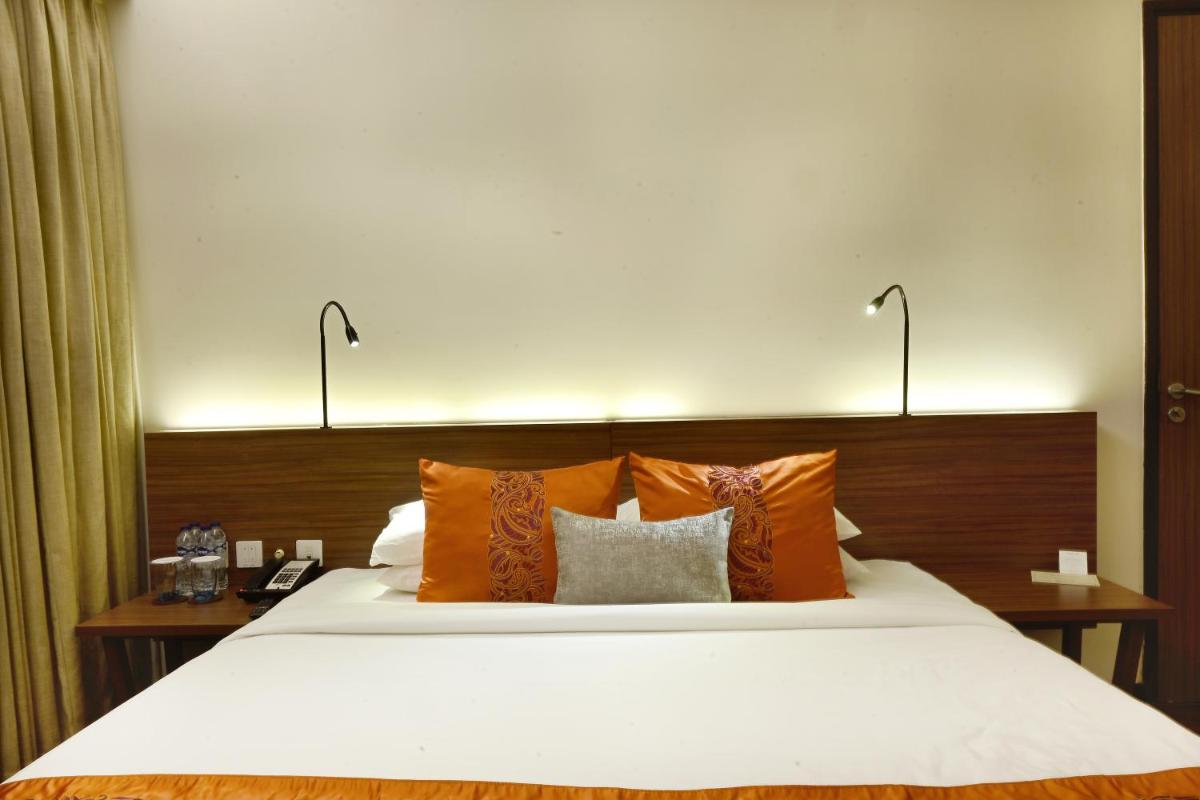 a bedroom with a large white bed with orange pillows at Vivanta Kolkata EM Bypass in Kolkata