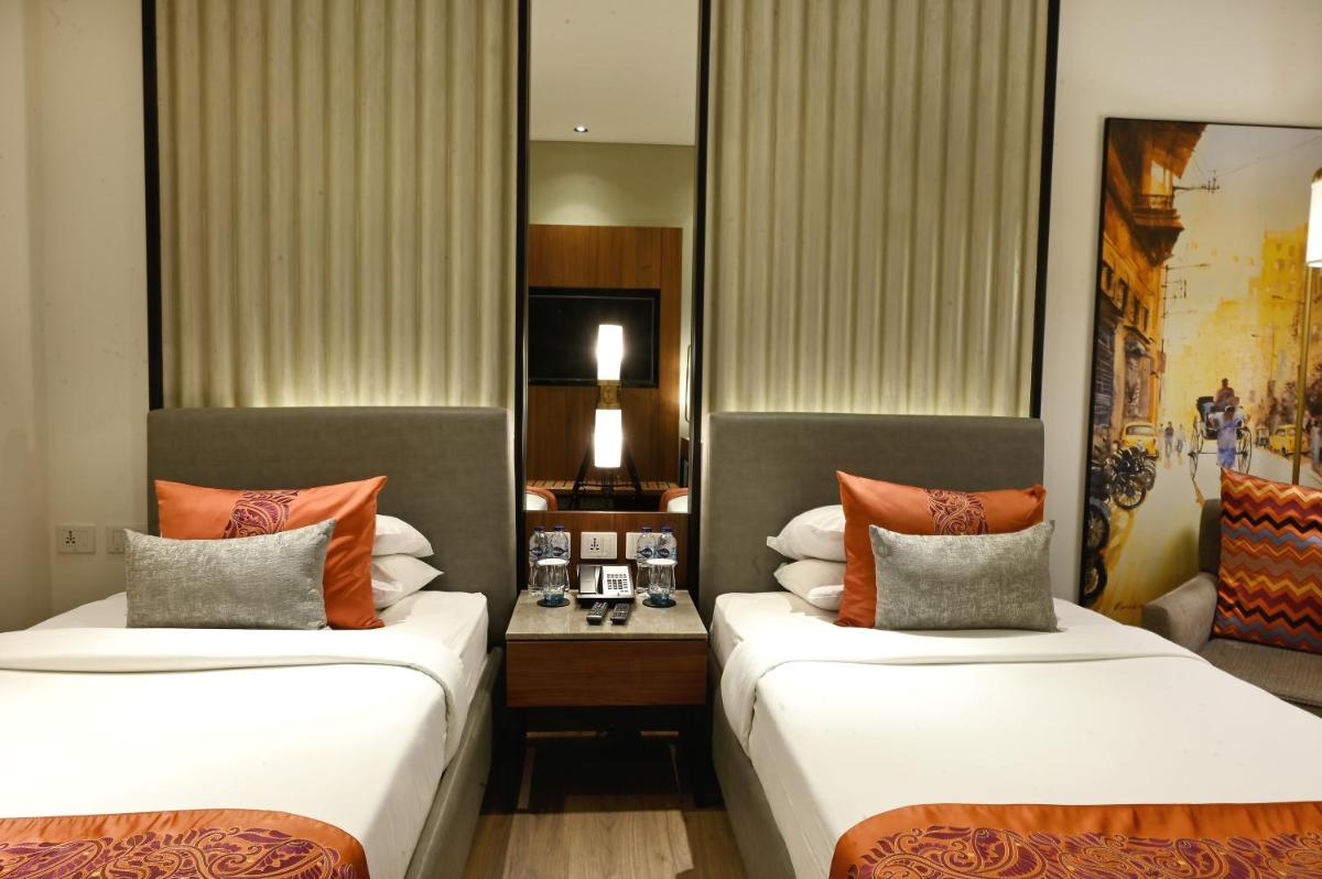a hotel room with two beds and a desk at Vivanta Kolkata EM Bypass in Kolkata