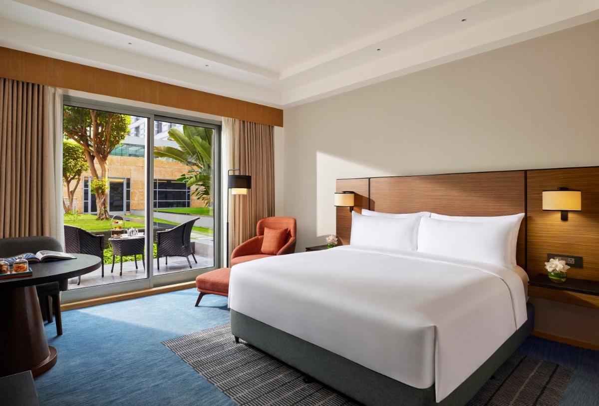 a bedroom with a large white bed and a balcony at Grand Hyatt Mumbai Hotel and Residences in Mumbai