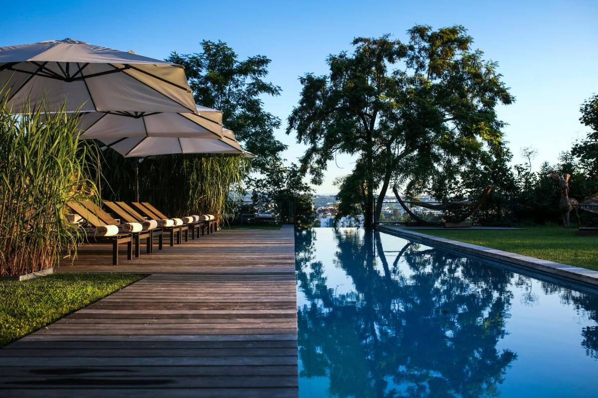 - une piscine avec des bancs et un parasol à côté de la piscine dans l'établissement Le Clos Des Sens, à Annecy - une piscine avec des bancs et un parasol à côté de la piscine dans l'établissement Le Clos Des Sens, à Annecy