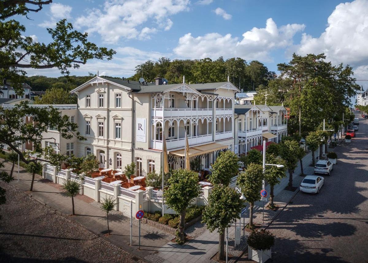 ein großes weißes Gebäude in einer Straße mit Bäumen in der Unterkunft ROEWERS Privathotel & Spa in Ostseebad Sellin