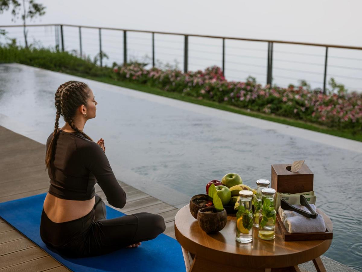 a woman sitting on a yoga mat next to a pool at The Westin Resort & Spa Himalayas in Rishīkesh