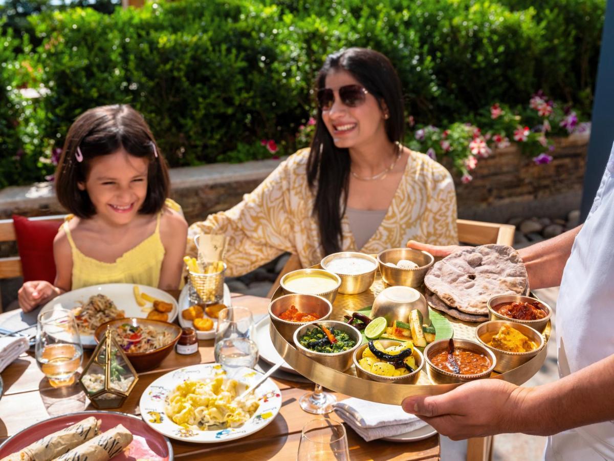 a woman and a girl sitting at a table with food at The Westin Resort & Spa Himalayas in Rishīkesh