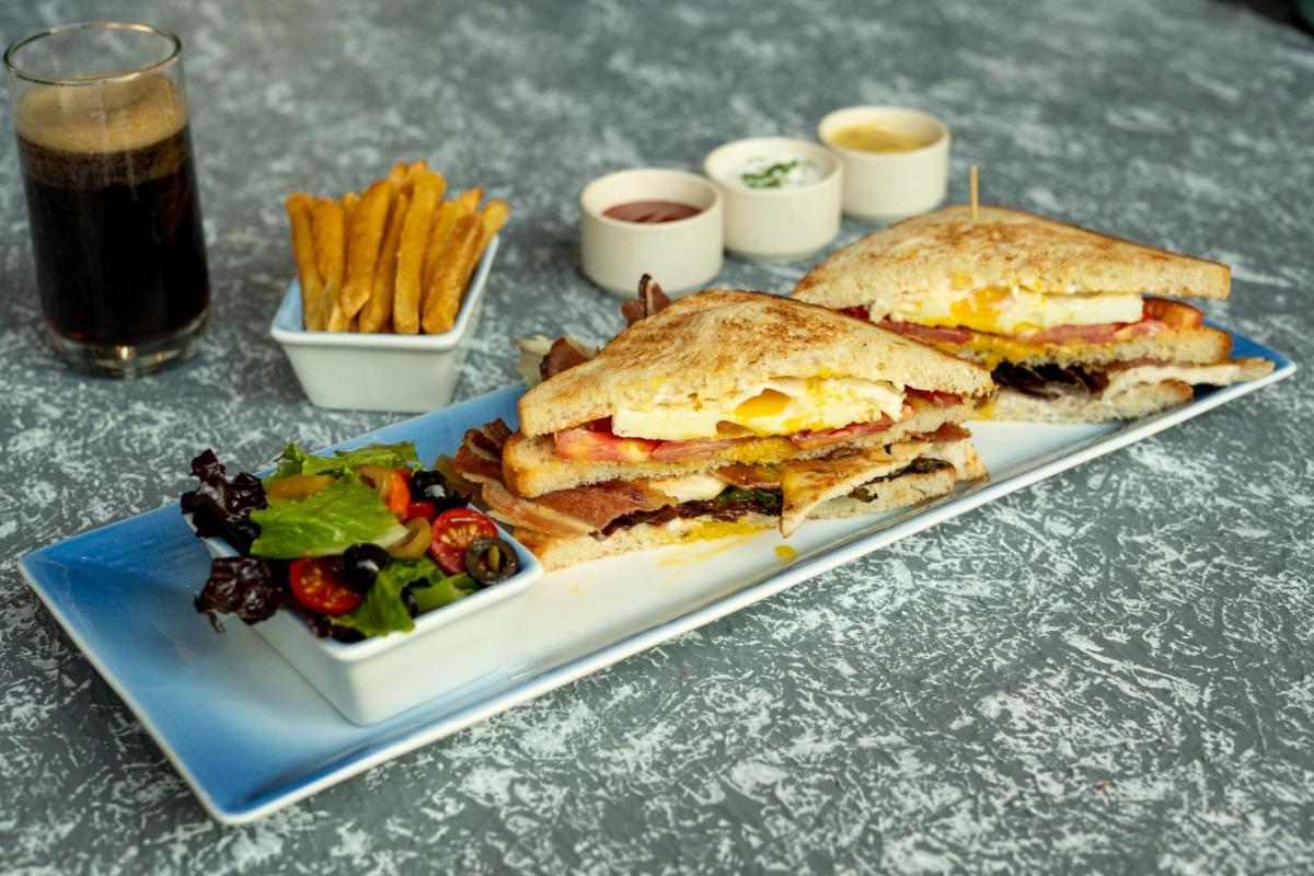 a sandwich and a salad on a plate with a drink at Hyatt Place Gurgaon Udyog Vihar in Gurgaon