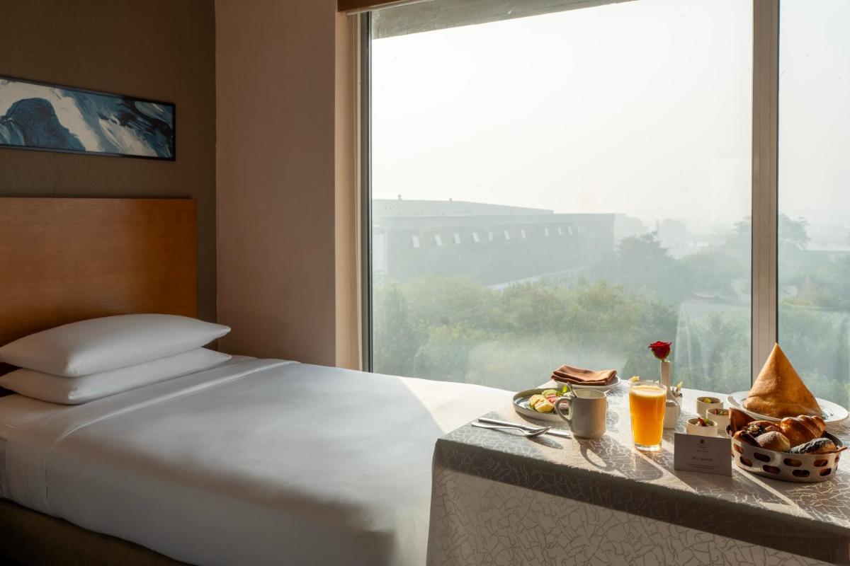 a hotel room with a bed and a table with food at Hyatt Place Gurgaon Udyog Vihar in Gurgaon