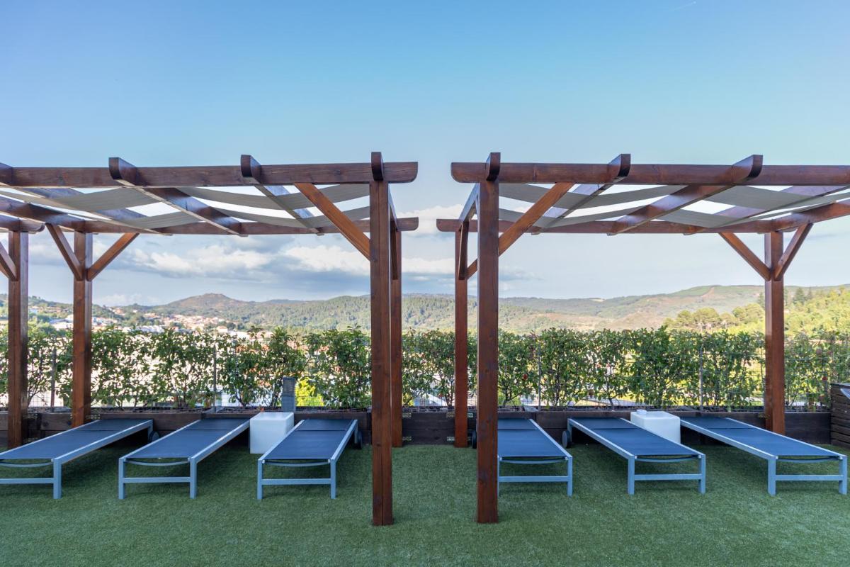 um grupo de cadeiras azuis sob uma pérgola de madeira em Boticas Hotel Art & SPA em Boticas