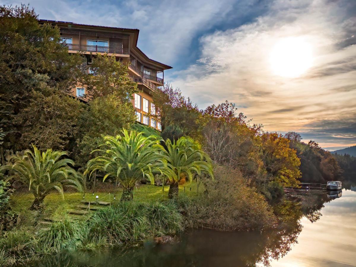 um edifício em uma colina ao lado de um rio em Hotel Rural Quinta da Conchada na Aguieira