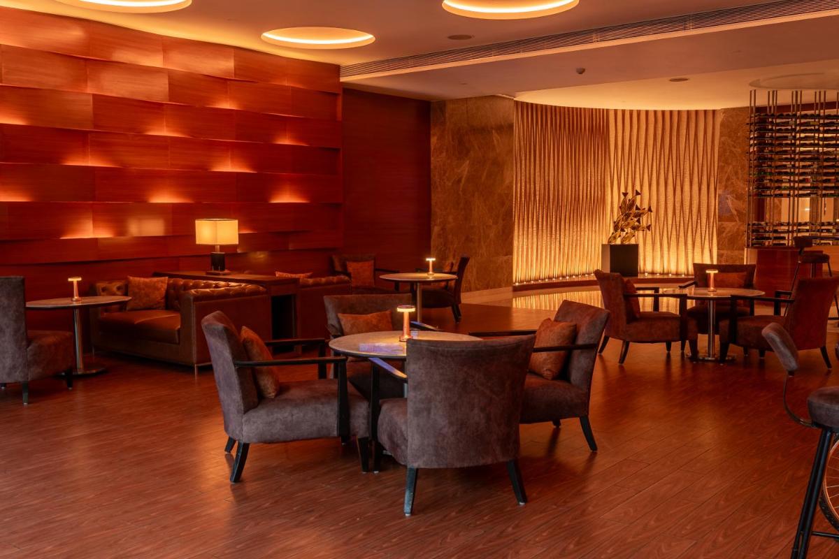 a restaurant with tables and chairs and a couch at Hyatt Pune in Pune