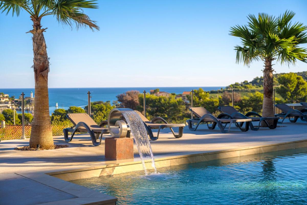 une fontaine devant une piscine avec des palmiers dans l'établissement Les Jardins du Cèdre, Boutique hôtel & gastronomie, à Port-Vendres