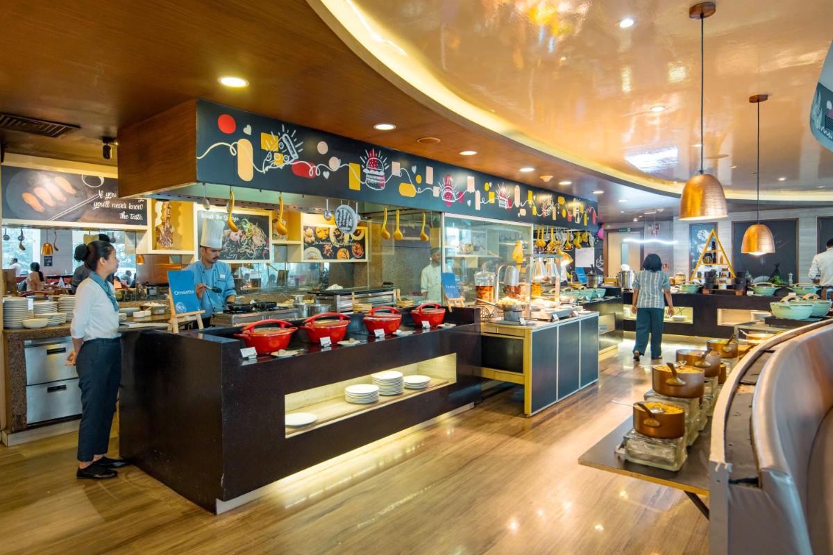 a restaurant with people preparing food in a kitchen at Novotel Ahmedabad in Ahmedabad