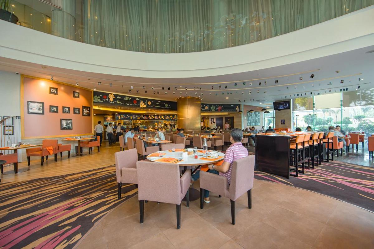 a person sitting at a table in a restaurant at Novotel Ahmedabad in Ahmedabad