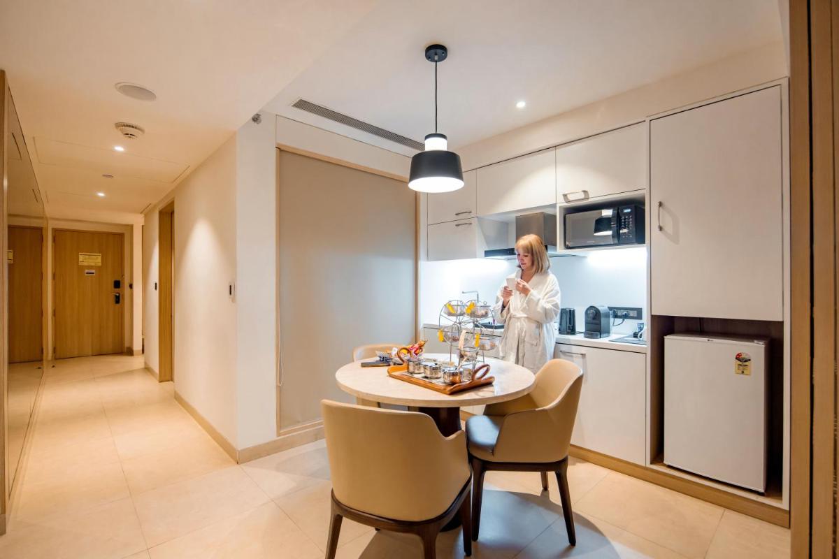 a woman standing in a kitchen with a table at Novotel Ahmedabad in Ahmedabad