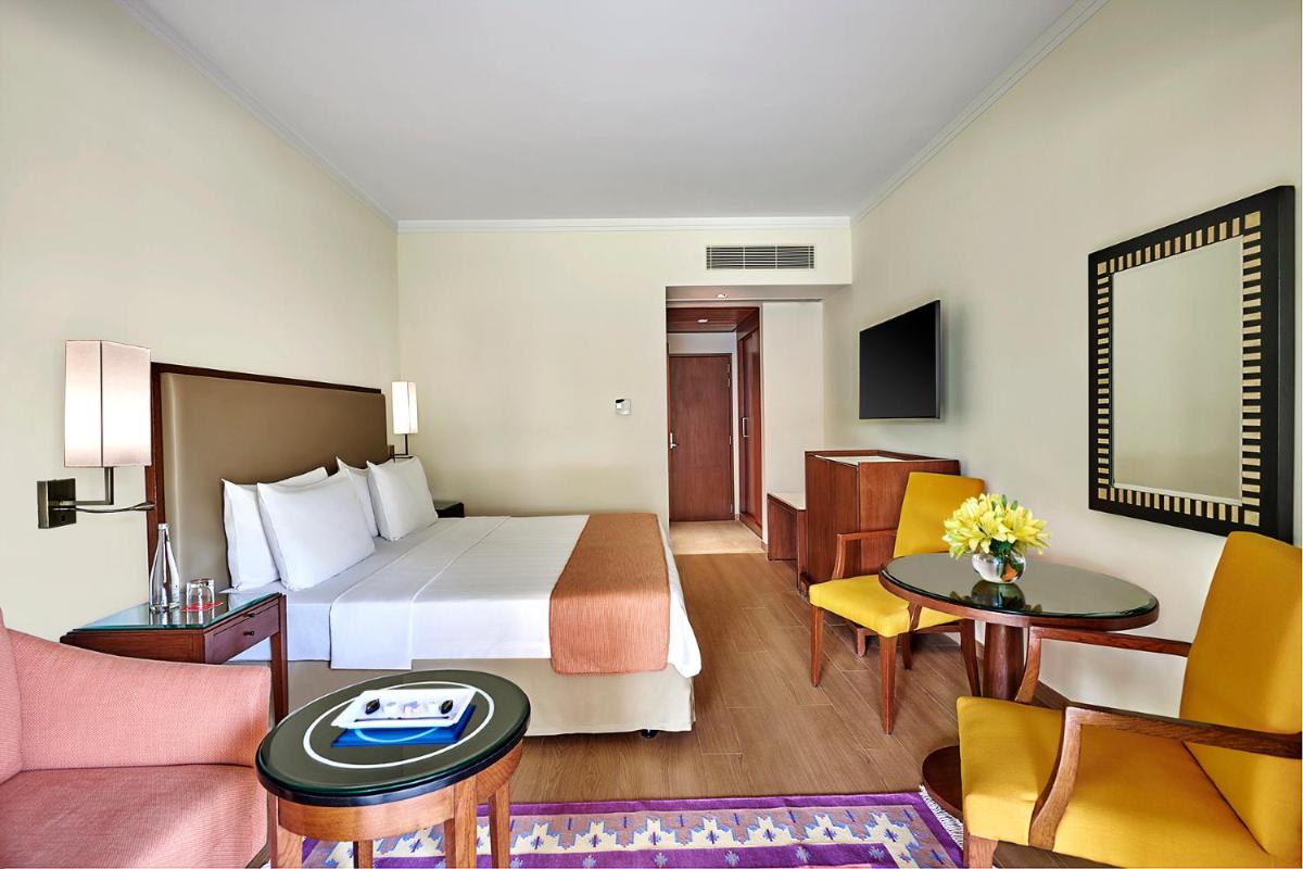 a hotel room with a bed and a living room at Trident Agra in Agra