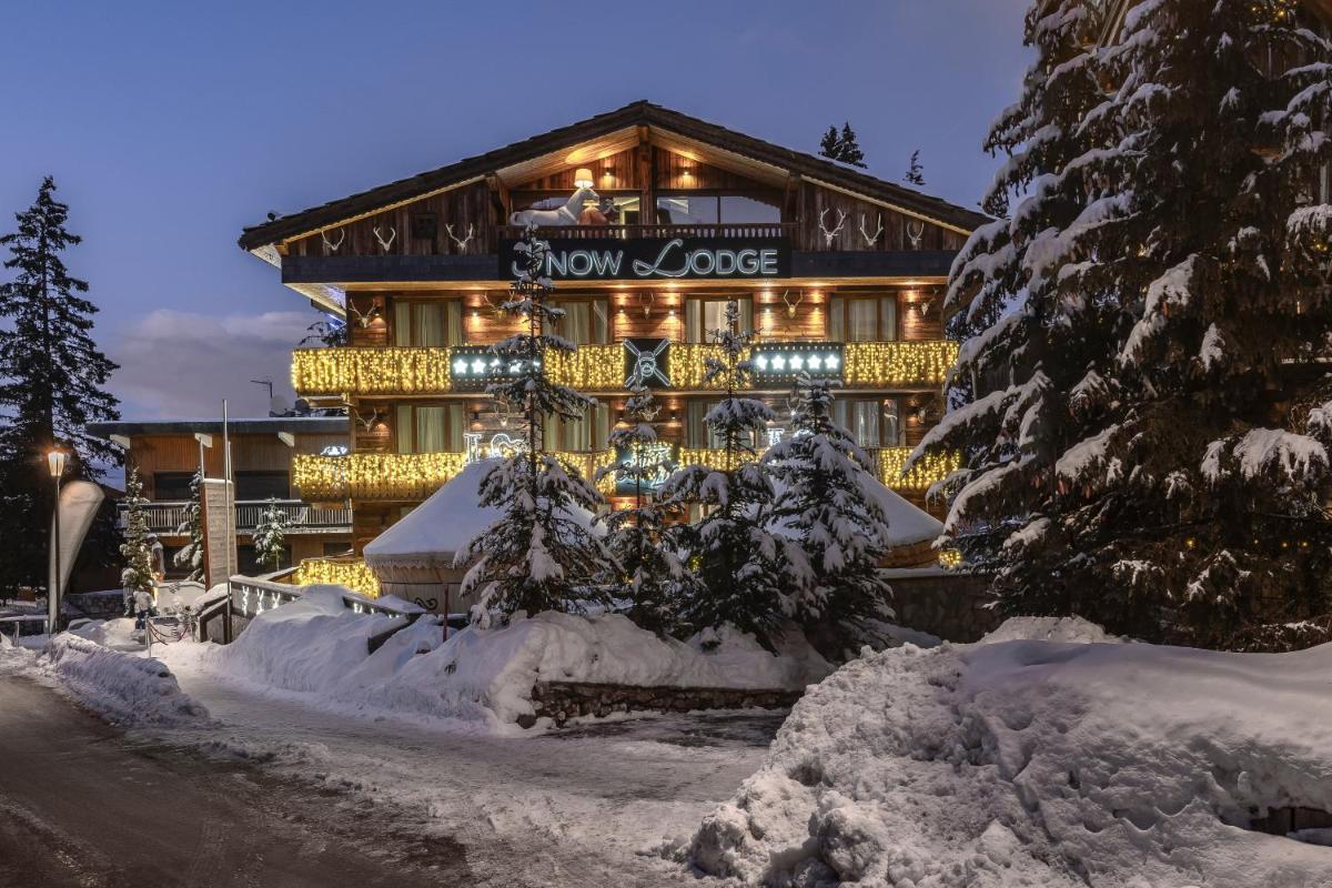 un grand bâtiment avec des arbres enneigés devant lui dans l'établissement Snow Lodge Hotel Courchevel 1850, à Courchevel