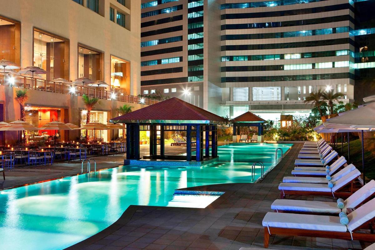 a swimming pool with lounge chairs and a building at The Westin Hyderabad Mindspace in Hyderabad