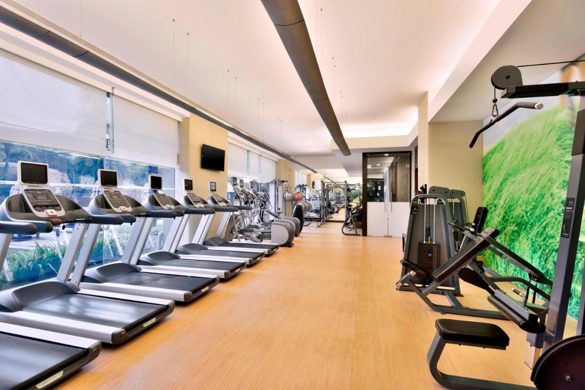 a gym with a row of treadmills and machines at The Westin Hyderabad Mindspace in Hyderabad