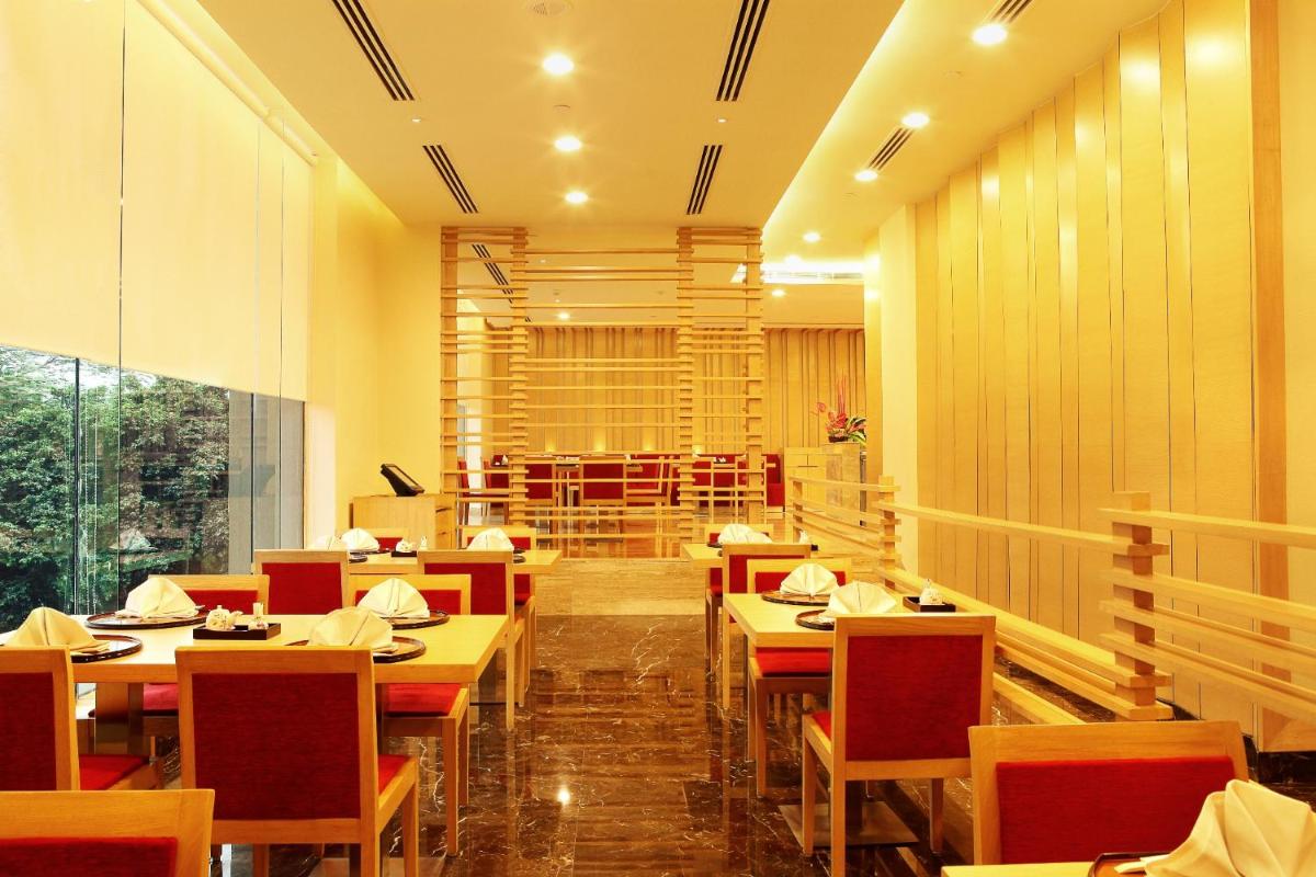 a restaurant with tables and chairs and a wine cellar at The Metropolitan Hotel & Spa New Delhi in New Delhi