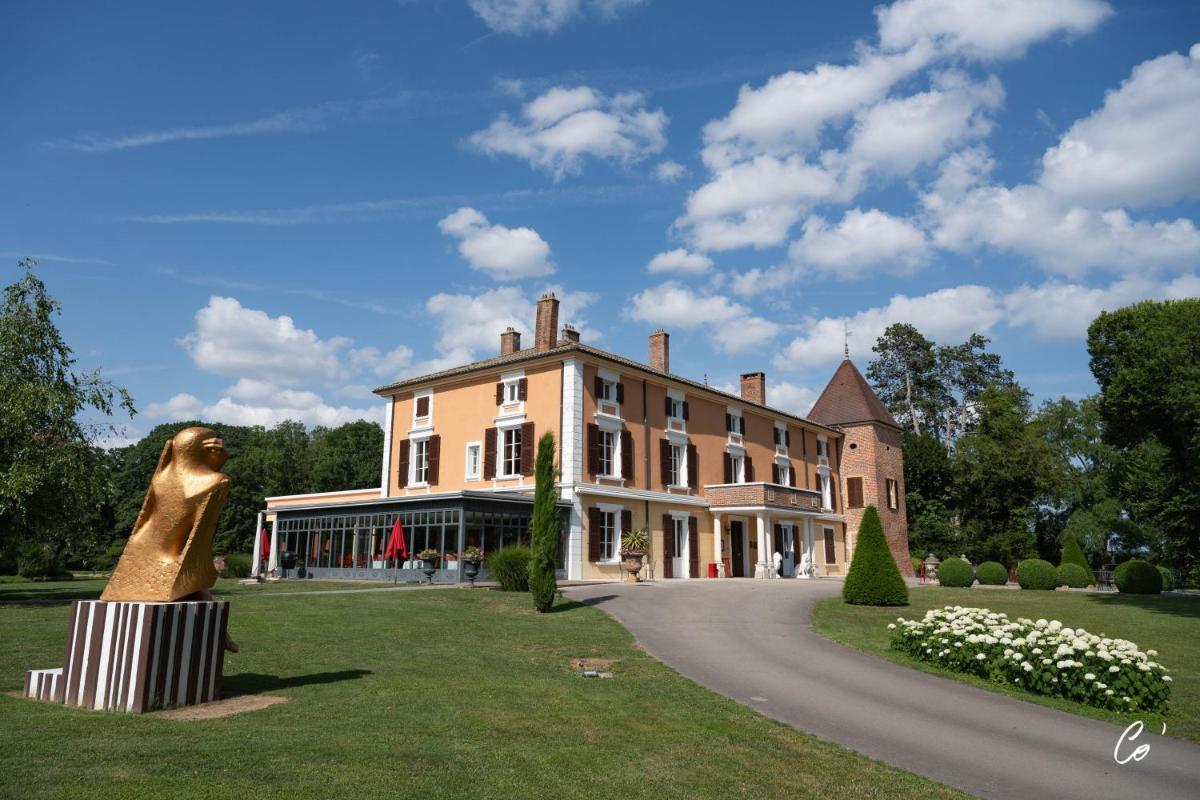 une grande maison avec une statue en face de celle-ci dans l'établissement Hôtel du Bois Blanc Domaine d'Epeyssoles Georges Blanc, à Vonnas