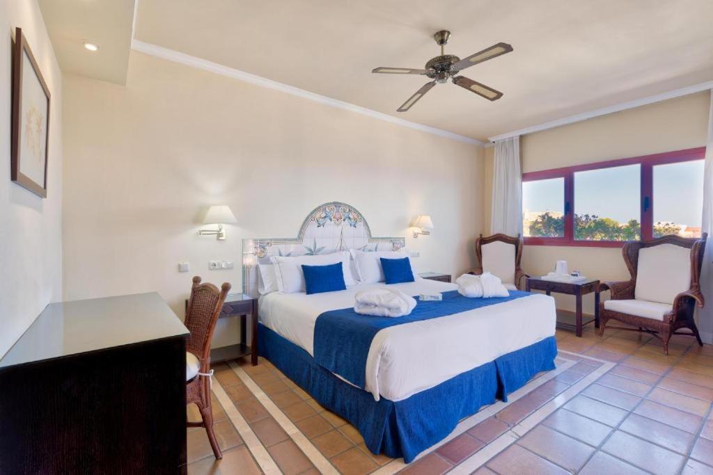 Un dormitorio con una cama con sábanas azules y blancas. en Ibersol Almuñecar Beach & Spa Hotel, en Almuñécar 54 fotos más
