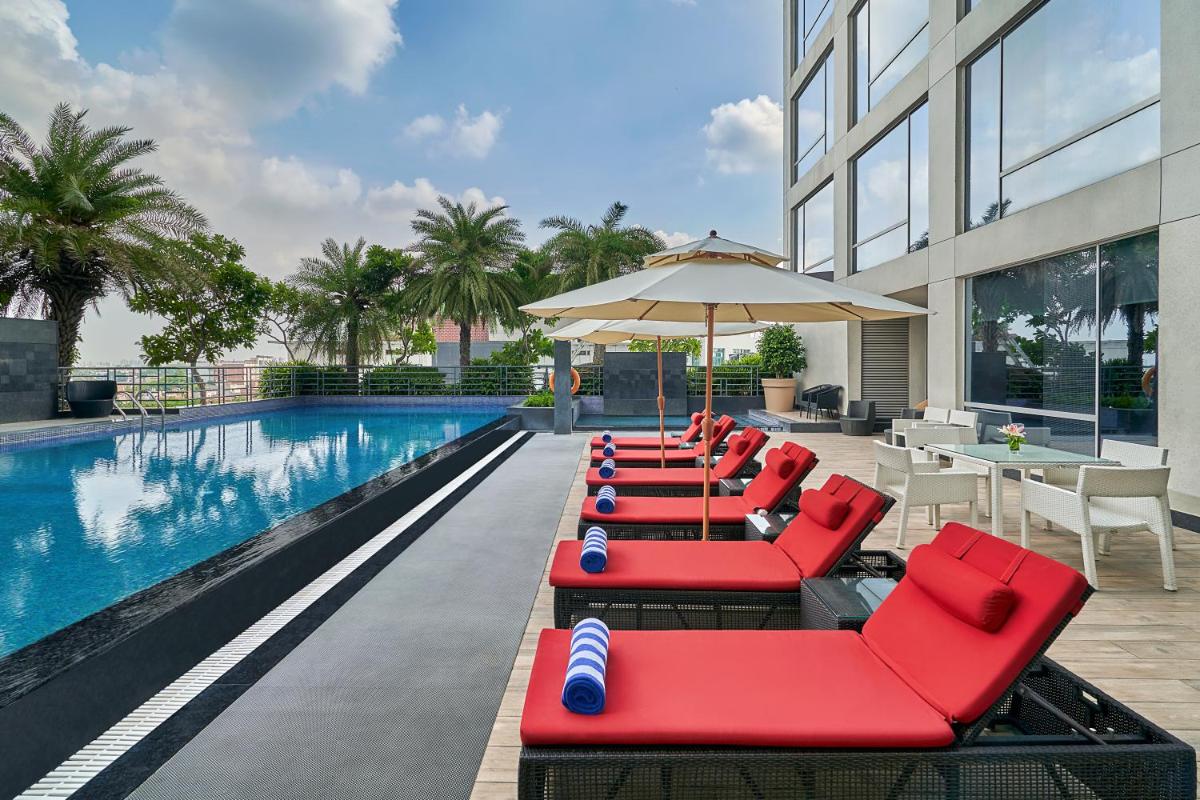 a row of red lounge chairs next to a swimming pool at Hyatt Regency Lucknow Gomti Nagar in Lucknow