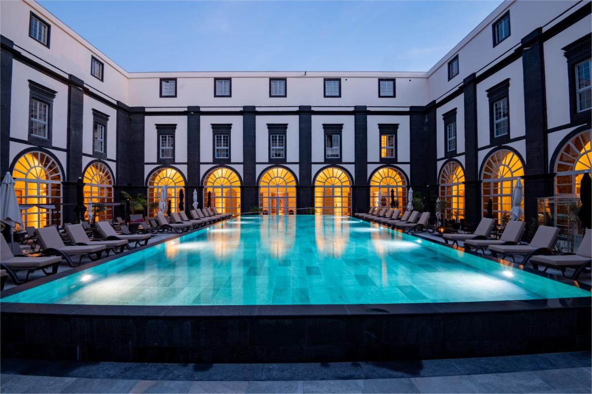 uma grande piscina num edifício com cadeiras e um edifício em Vila Gale Collection S.Miguel em Ponta Delgada