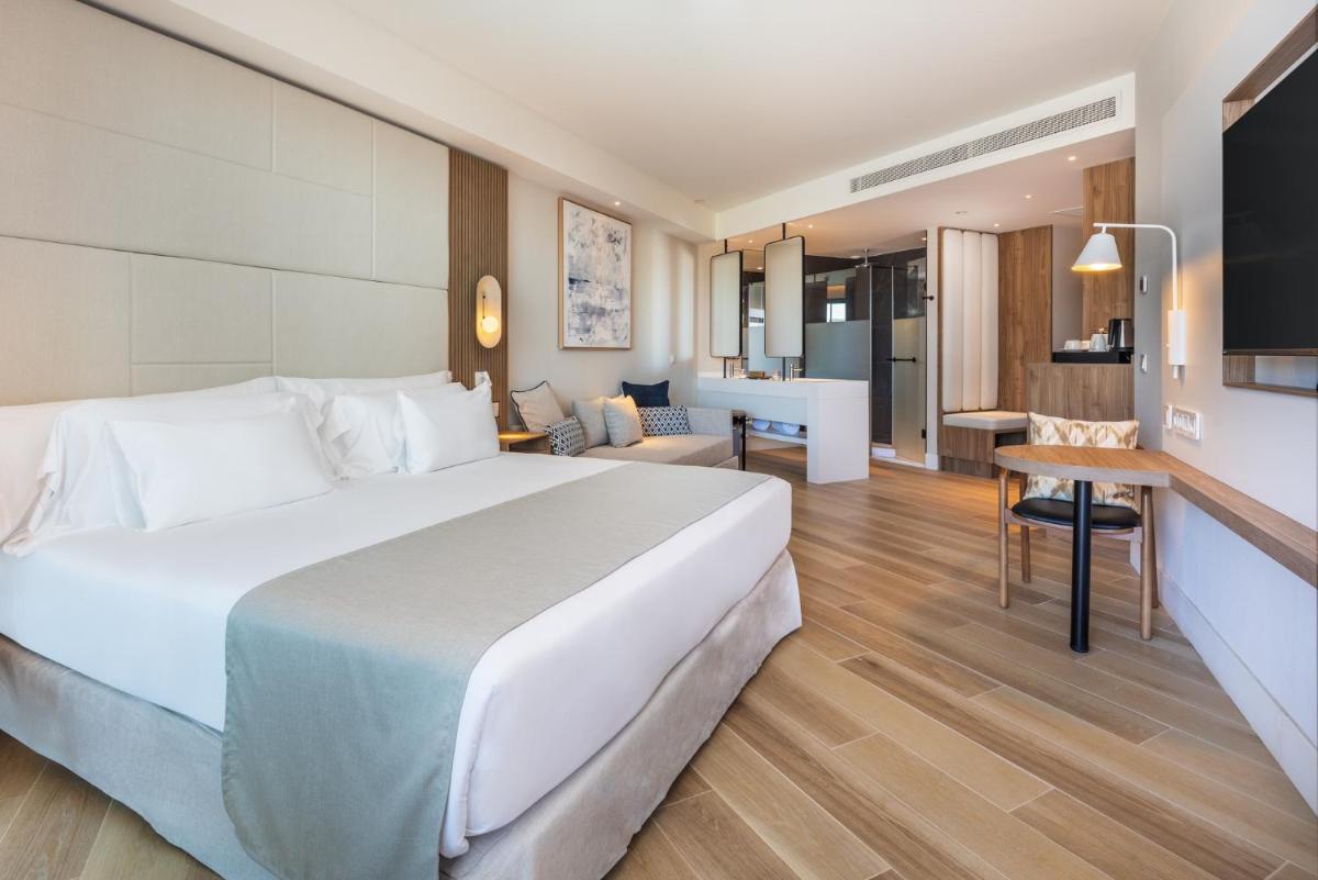 Un dormitorio con una cama grande y una sala de estar. en Barceló Playa Blanca Royal Level - Adults Only, en Playa Blanca