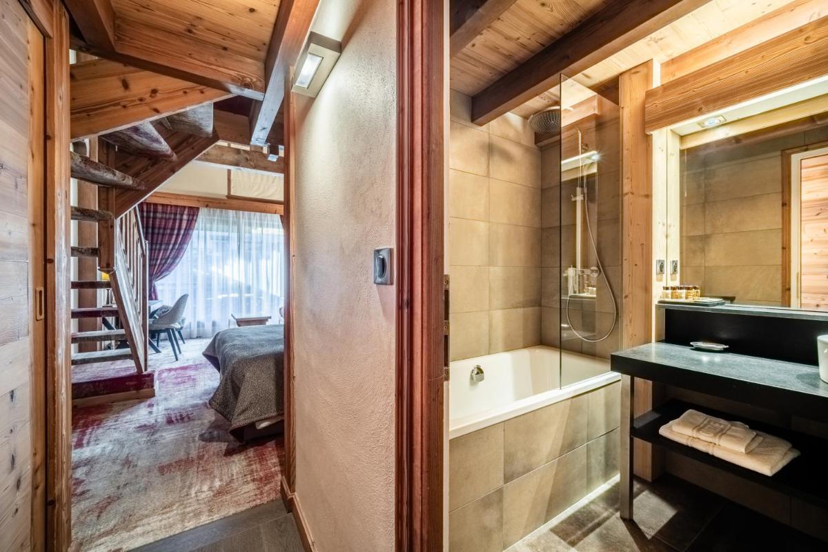 une salle de bain avec une baignoire et un lavabo et un lit dans l'établissement Hotel Le Samoyede, à Morzine 118 autres photos